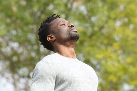 Man taking deep breath outside